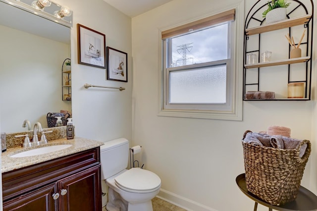 bathroom with baseboards, toilet, and vanity