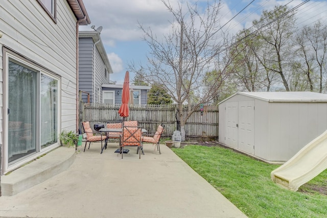 view of patio featuring a storage shed, an outbuilding, outdoor dining area, and a fenced backyard