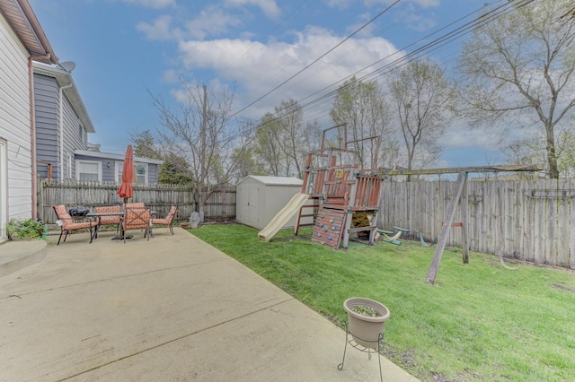 view of yard featuring an outbuilding, a fenced backyard, a playground, a patio area, and a shed