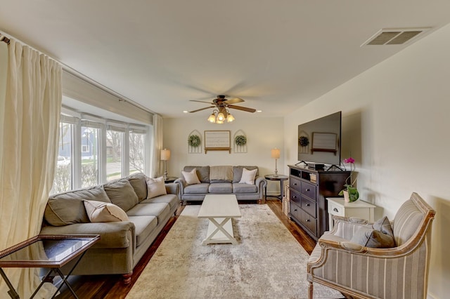 living area with dark wood-style floors, ceiling fan, and visible vents