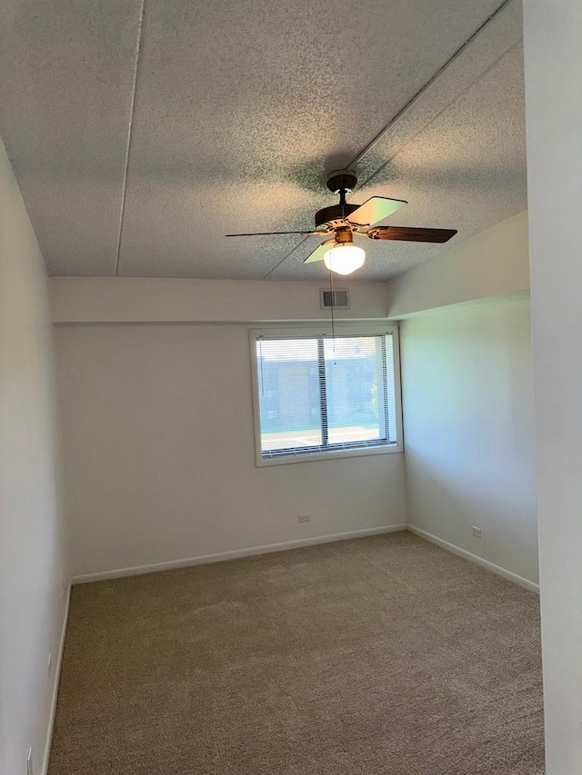 carpeted spare room with ceiling fan, a textured ceiling, and baseboards