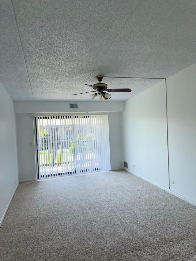 carpeted spare room with ceiling fan, baseboards, and a textured ceiling