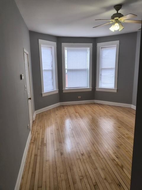 interior space featuring light wood-style flooring, baseboards, and a ceiling fan