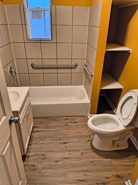 full bath with wood finished floors, toilet, vanity, and shower / bathtub combination