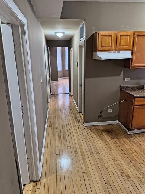 hallway featuring light wood-style floors and baseboards
