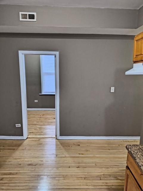 unfurnished dining area featuring wood-type flooring, visible vents, and baseboards