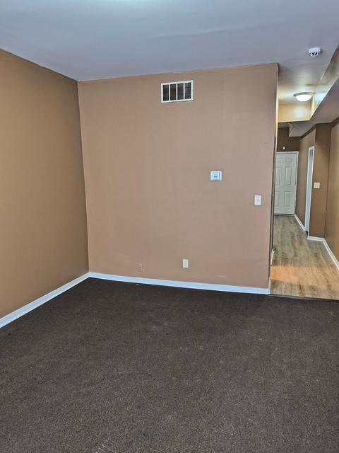 spare room featuring baseboards, visible vents, and carpet flooring