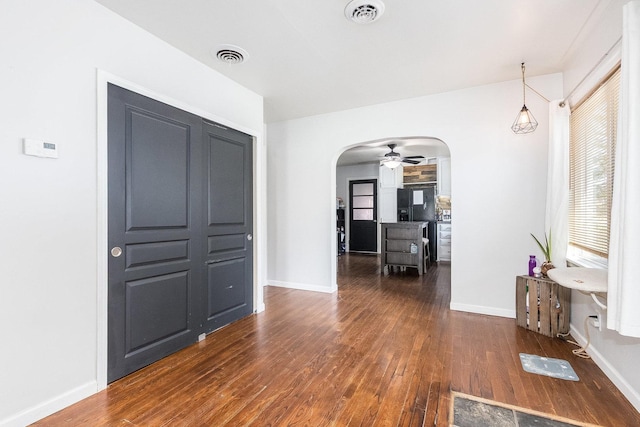 foyer entrance with visible vents, arched walkways, baseboards, and wood finished floors