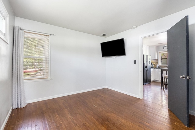 spare room featuring baseboards and dark wood-type flooring