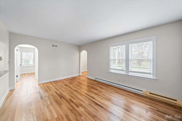 unfurnished room with a baseboard heating unit, light wood-style flooring, arched walkways, baseboards, and visible vents