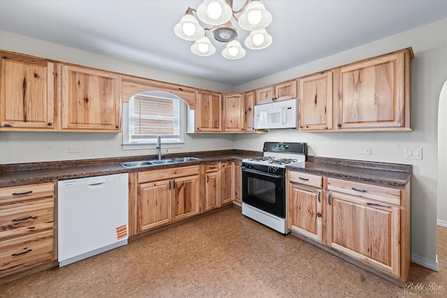 kitchen featuring dark countertops, a chandelier, a sink, and white appliances