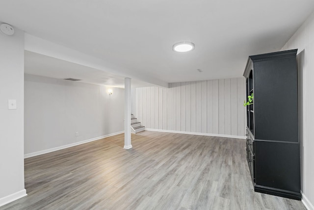 finished below grade area with baseboards, visible vents, stairs, and light wood finished floors