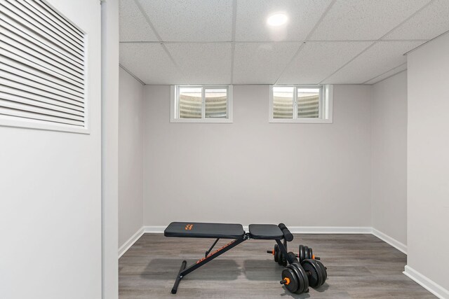 exercise room featuring baseboards, wood finished floors, and a drop ceiling