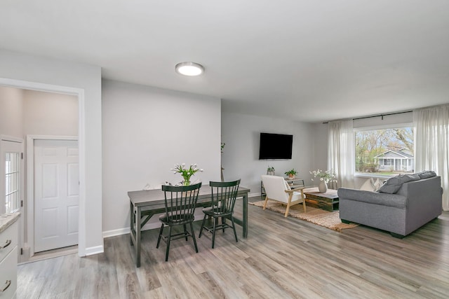 dining space with baseboards and light wood-style floors