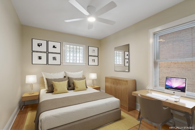 bedroom with baseboards, a ceiling fan, and light wood-style flooring