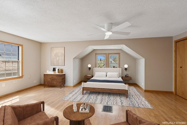 bedroom featuring multiple windows, light wood finished floors, and a textured ceiling
