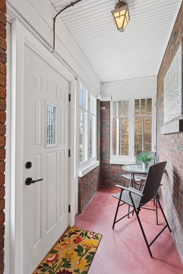 sunroom / solarium featuring brick wall