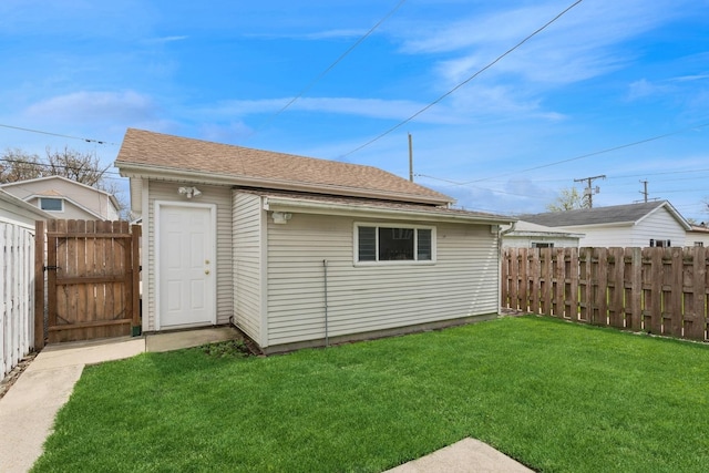 back of property featuring a lawn, fence, a gate, and an outdoor structure