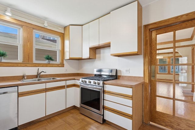 kitchen with light countertops, a sink, white cabinets, and stainless steel appliances