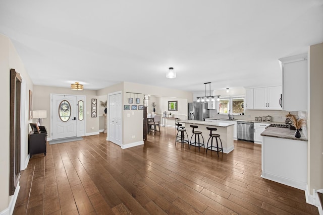 interior space featuring a center island, dark wood finished floors, baseboards, white cabinets, and stainless steel appliances