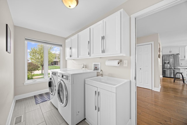laundry room with independent washer and dryer, visible vents, cabinet space, a sink, and baseboards