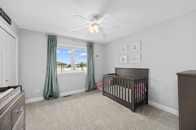 bedroom with baseboards, carpet, a closet, and a crib