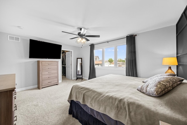 bedroom with visible vents, baseboards, ceiling fan, light colored carpet, and a spacious closet
