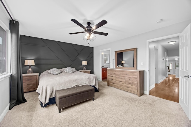 bedroom featuring baseboards, light colored carpet, ceiling fan, and ensuite bathroom