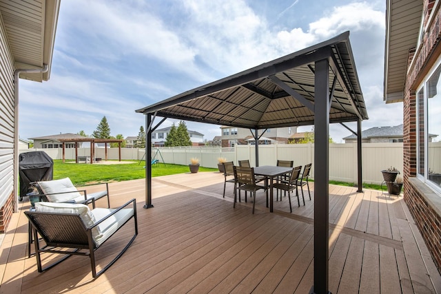wooden deck with grilling area, a gazebo, a fenced backyard, a yard, and outdoor dining space