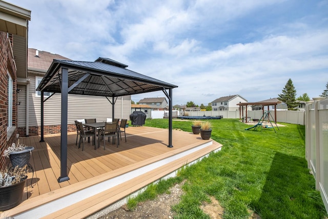 deck with a gazebo, a fenced backyard, outdoor dining area, a playground, and a yard
