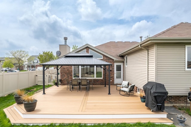 rear view of property featuring fence, outdoor dining space, a gazebo, and a wooden deck
