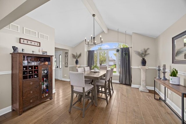 dining space featuring wood-type flooring, a notable chandelier, visible vents, and baseboards