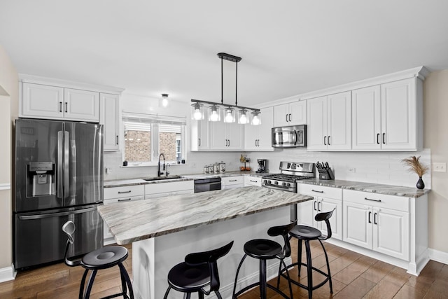 kitchen with dark wood-style flooring, a kitchen bar, appliances with stainless steel finishes, a sink, and white cabinets