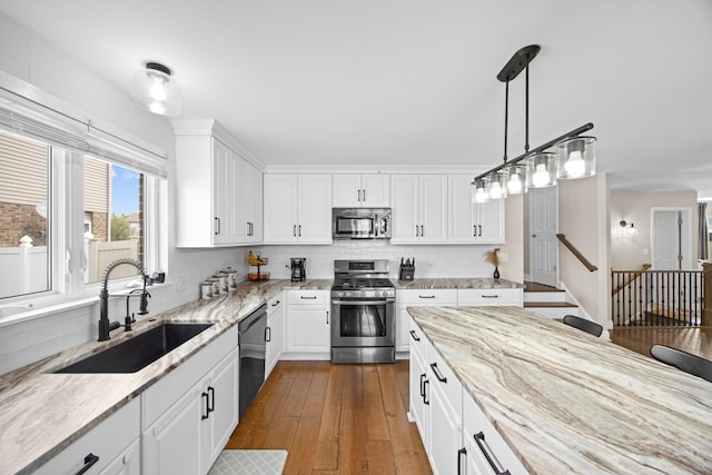 kitchen featuring dark wood-style flooring, white cabinetry, light stone counters, a sink, and stainless steel appliances