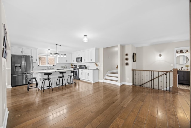 living room with baseboards, an inviting chandelier, stairway, and dark wood-type flooring
