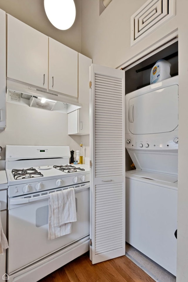 kitchen with white cabinets, stacked washer and dryer, white gas range oven, light wood-style flooring, and under cabinet range hood