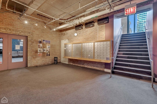 interior space featuring stairway, brick wall, carpet floors, and mail area