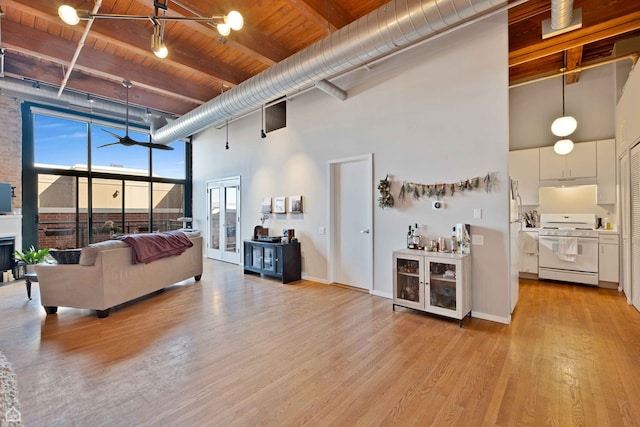 living area with a high ceiling, a ceiling fan, beamed ceiling, light wood-type flooring, and wood ceiling