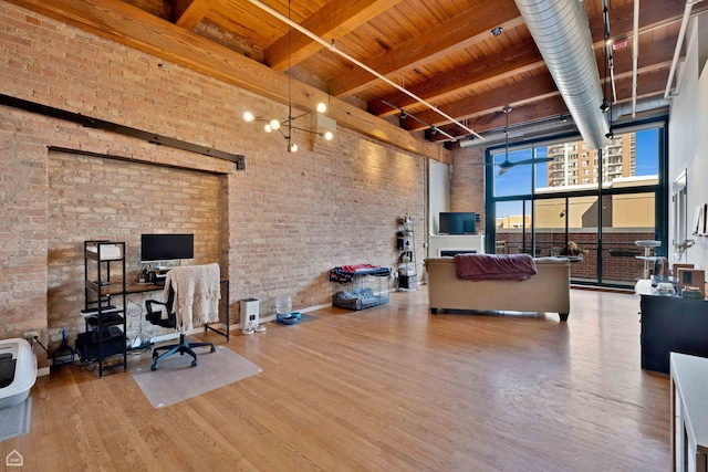 interior space featuring wood ceiling, brick wall, wood finished floors, and a towering ceiling