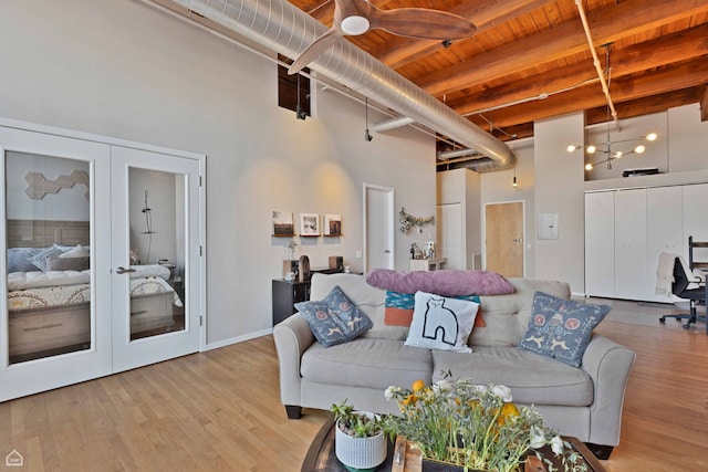 living room featuring french doors, beamed ceiling, a high ceiling, wood finished floors, and wooden ceiling
