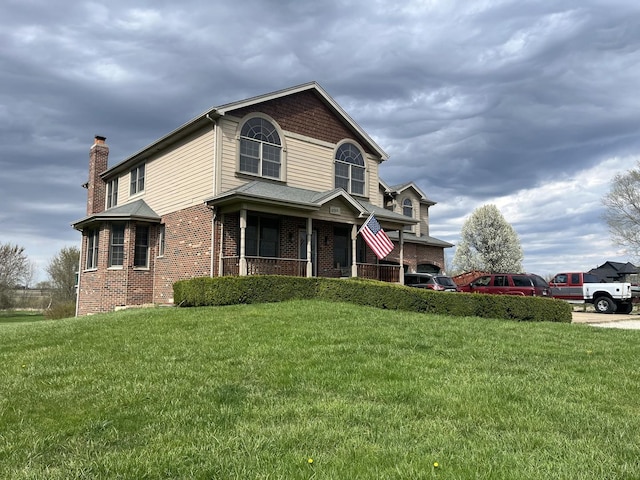 traditional home featuring a front lawn, brick siding, covered porch, and a chimney