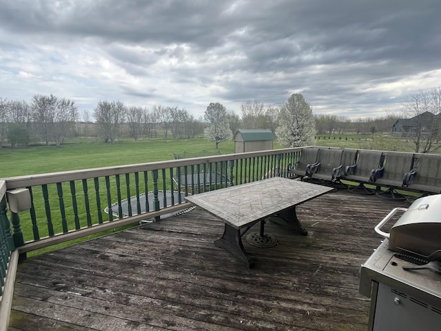 wooden deck with an outdoor structure, a lawn, and a shed