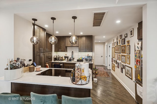 kitchen with dark brown cabinets, a sink, visible vents, stainless steel refrigerator, and black electric stovetop