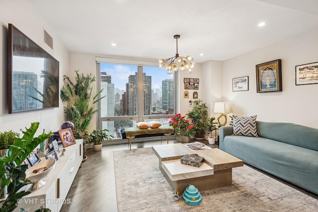 living room featuring wood finished floors, a view of city, recessed lighting, visible vents, and a chandelier