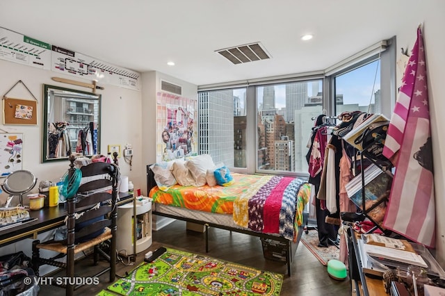 bedroom featuring recessed lighting, a city view, visible vents, and wood finished floors
