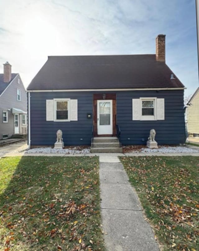 view of front of property with a chimney, entry steps, and a front lawn