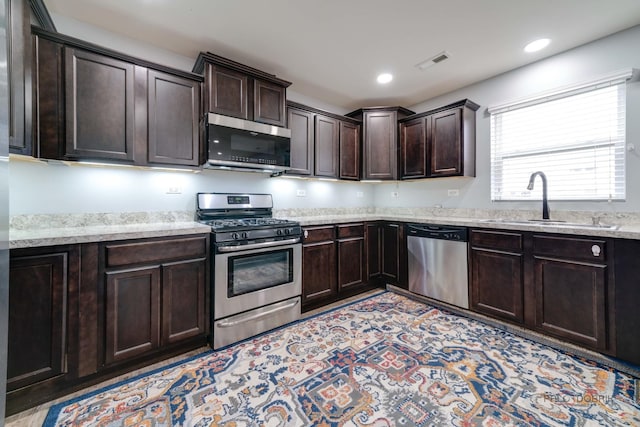 267 Maryland Ln, Pingree Grove, IL 60140 - kitchen featuring a sink, dark brown cabinets, visible vents, light stone countertops, and appliances with stainless steel finishes