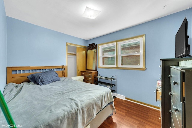 bedroom with wood finished floors, a closet, baseboards, and visible vents