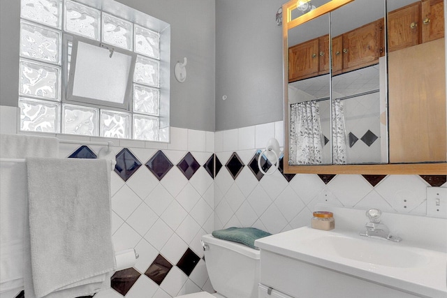 full bath featuring a shower with shower curtain, tile walls, toilet, and vanity