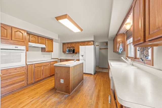 2398 S Williamsburg Dr, Plainfield, IL 60586 - kitchen featuring white appliances, under cabinet range hood, an island with sink, light wood-style flooring, and light countertops